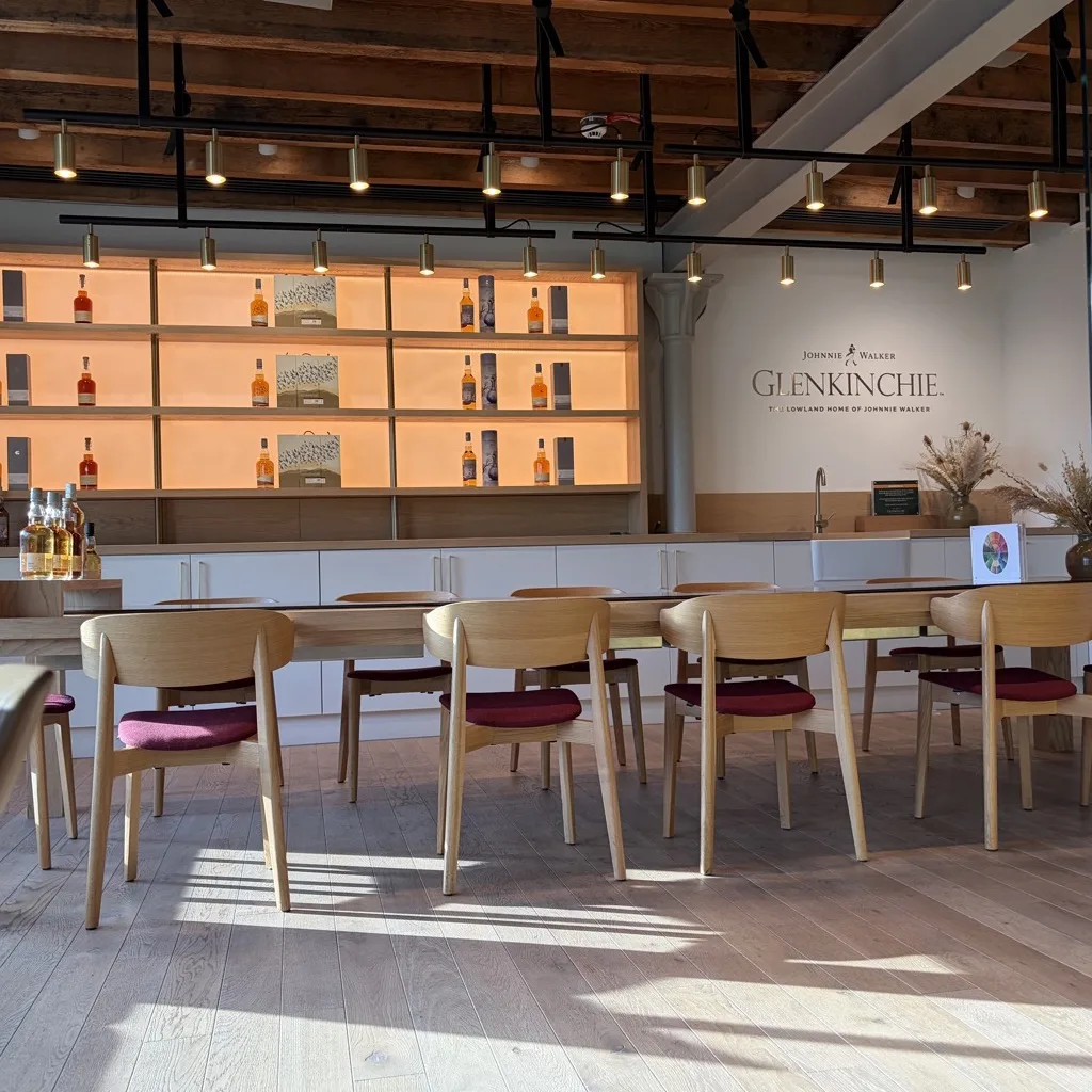 Der moderne Tasting-Raum von Glenkinchie mit beleuchteten Regalen und dem Johnnie-Walker-Glenkinchie-Schriftzug an der Wand